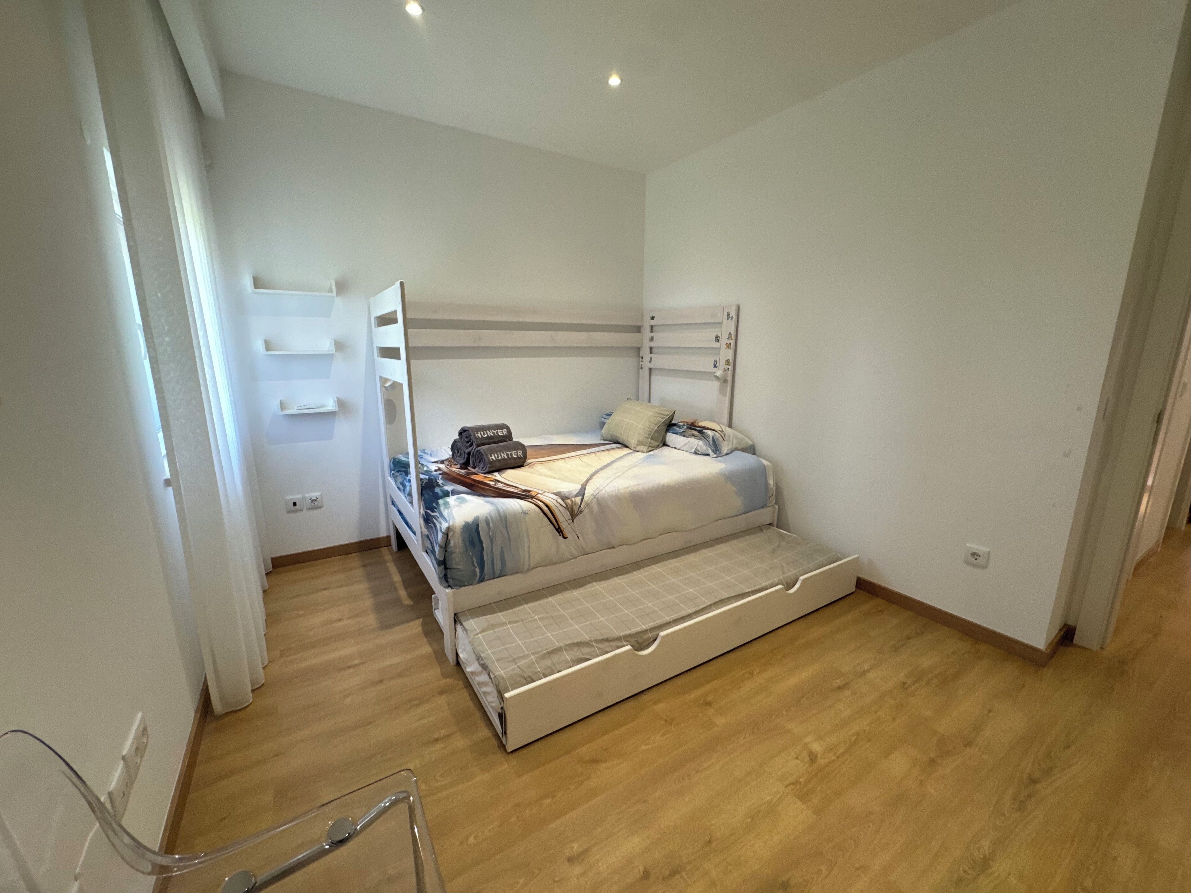 A bedroom with a bunk bed, a pull-out sofa, and a bedside table.