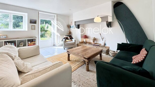 Una sala de estar moderna con un sofá, una mesa de centro y un sillón verde. Hay una estantería y una lámpara en la habitación.