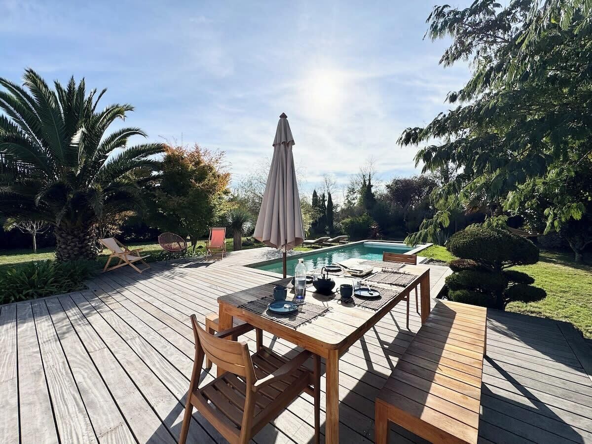 A wooden deck with a pool table, chairs, and an umbrella.