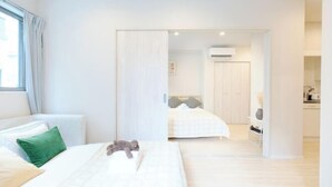Una habitación de hotel moderna con una cama grande, una mesita de noche pequeña y vistas al pasillo.