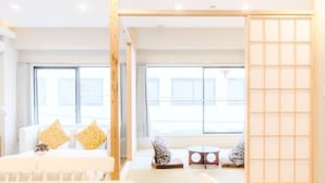 Una habitación de hotel moderna con cama, zona de estar y ventanas amplias.