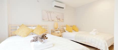 A hotel room with two beds, a wall-mounted air conditioner, and a framed picture.