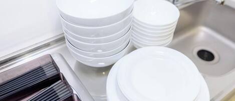 Un coin cuisine comprenant un évier, une pile d’assiettes blanches et une cuisinière.