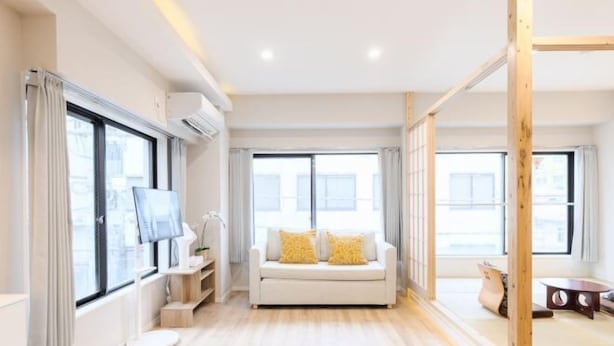 Una sala de estar moderna con sofá, televisor y piso de madera.