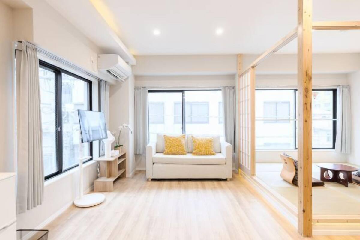 A modern living room with a sofa, TV, and wooden flooring.