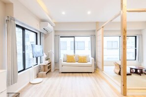 Un salon moderne avec un canapé, un téléviseur et un plancher en bois.