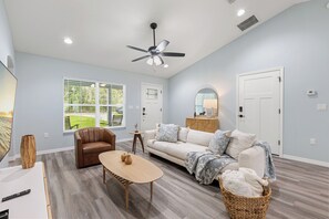 Un salon spacieux doté d’un ventilateur de plafond, d’un canapé, d’une table basse et d’un téléviseur.