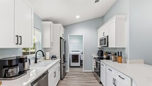 A modern kitchen with white cabinets, stainless steel appliances, and a central island.