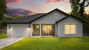 A single-story house with a garage, a front porch with seating, and a well-maintained lawn.