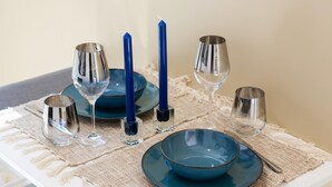 Une table à manger dressée avec de l’argenterie, des assiettes bleues et des bougies.