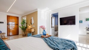 Une chambre d’hôtel moderne avec un grand lit, une télévision, une salle de bain et une porte en bois.