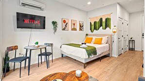 Een moderne slaapkamer met een bed, nachtkastje en een televisie waarop 'NETFLIX' wordt weergegeven.