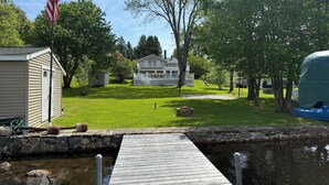 A house with a dock extending into a pond, surrounded by a well-maintained lawn and trees. - Lakefront Escape on Highland (Winchester)