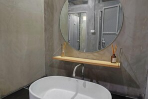 A bathroom with a freestanding bathtub, a round mirror, and a wooden shelf with a bottle of soap. - Siam Breeze Inn (Self check-in) (Bangkok)
