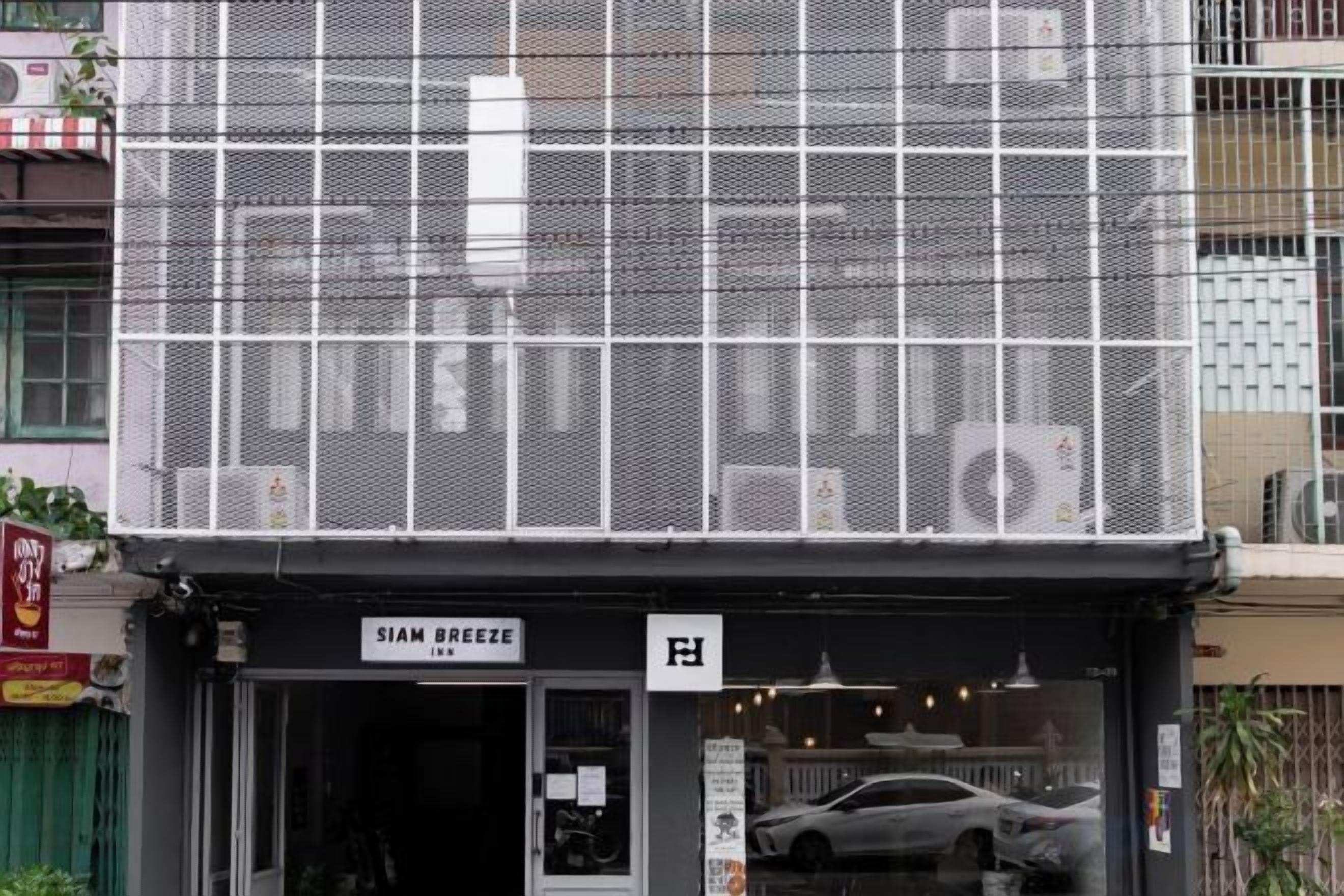 Un edificio con fachada de malla y un letrero que dice 'SIAM BREEZE' en la entrada.