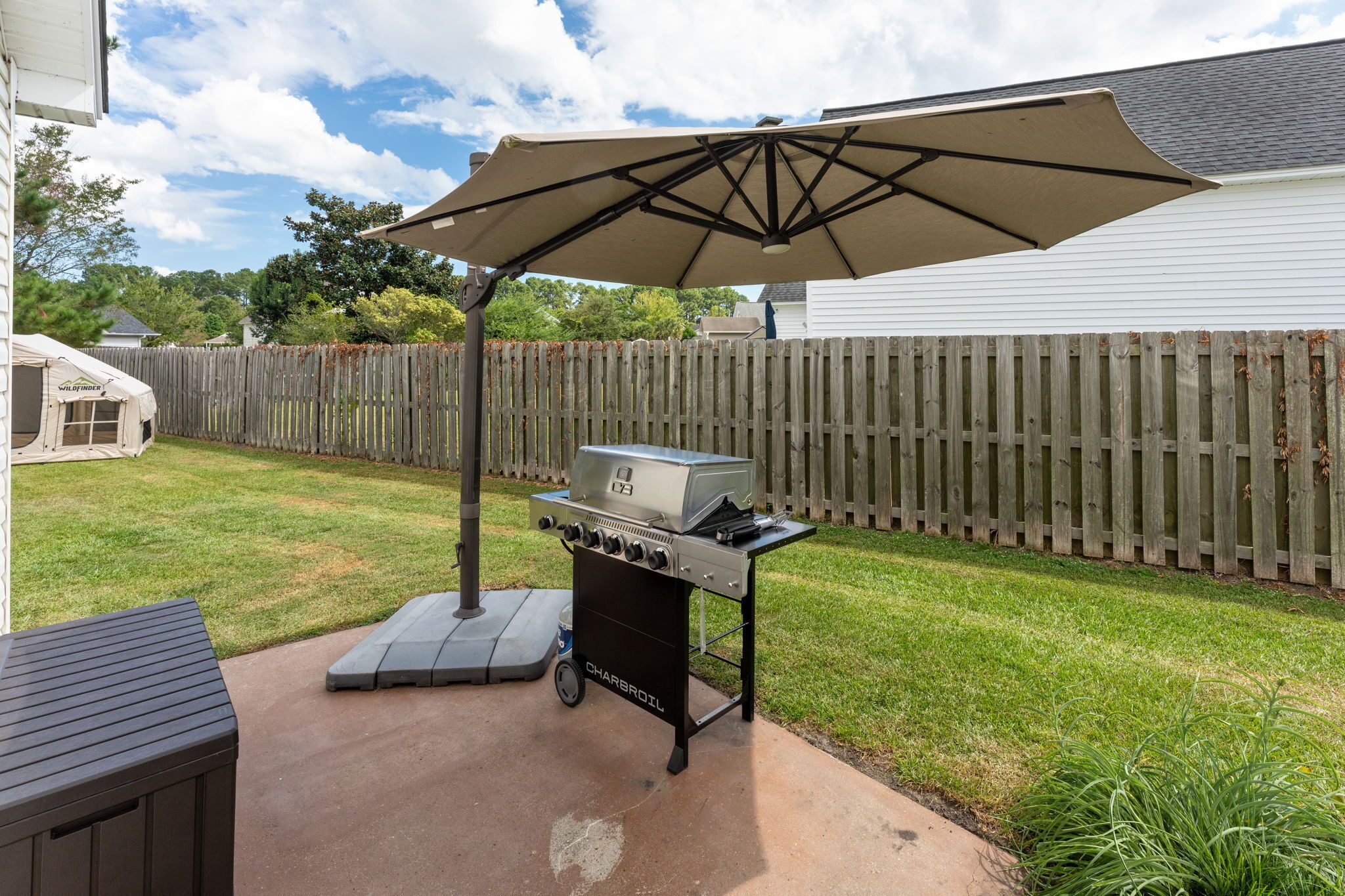 An outdoor barbecue grill with a canopy, a portable table, and a wooden fence in the background.
