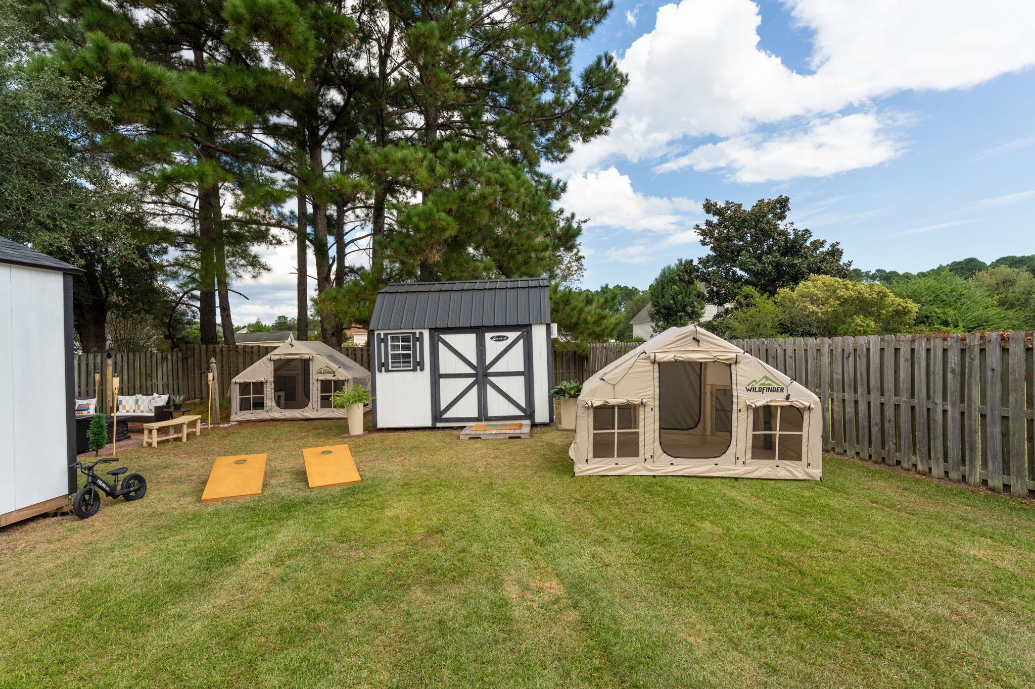 A backyard with a small shed, two playhouses, and a wooden fence.