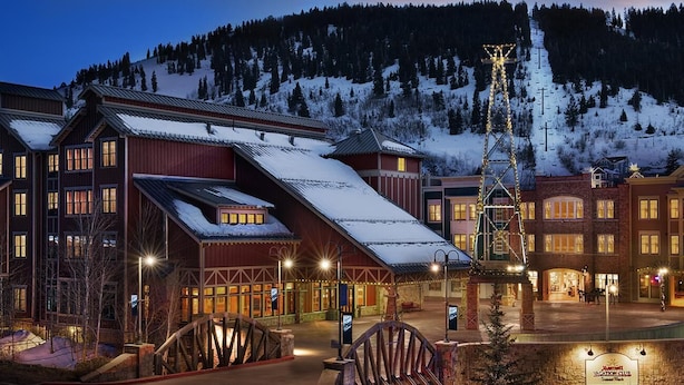Et hotel med rustikt udseende, flere etager og en tydelig skilift i baggrunden.