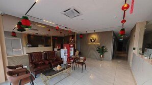 Un vestíbulo de hotel con mostrador de recepción, zona de estar y mostrador de información.