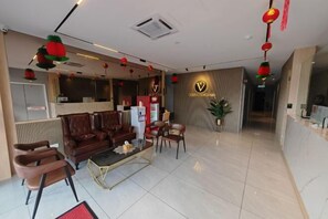 Een hotellobby met een receptiebalie, een zithoek en een receptiecounter.