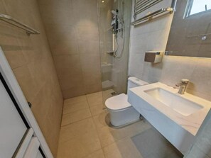Een badkamer met douche, toilet en wastafel.