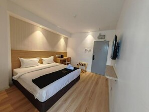 Een moderne hotelkamer met een groot bed, nachtkastje en een flatscreen televisie aan de muur.