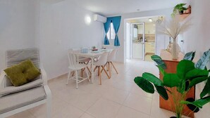 A modern living room with a dining area, white furniture, and a large green plant. - Beautiful home in Fuengirola with WiFi (Fuengirola)