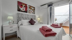 A bedroom with a bed, two nightstands, a marble headboard, two wall-mounted lamps, and a balcony with a railing. - Beautiful home in Fuengirola with WiFi (Fuengirola)