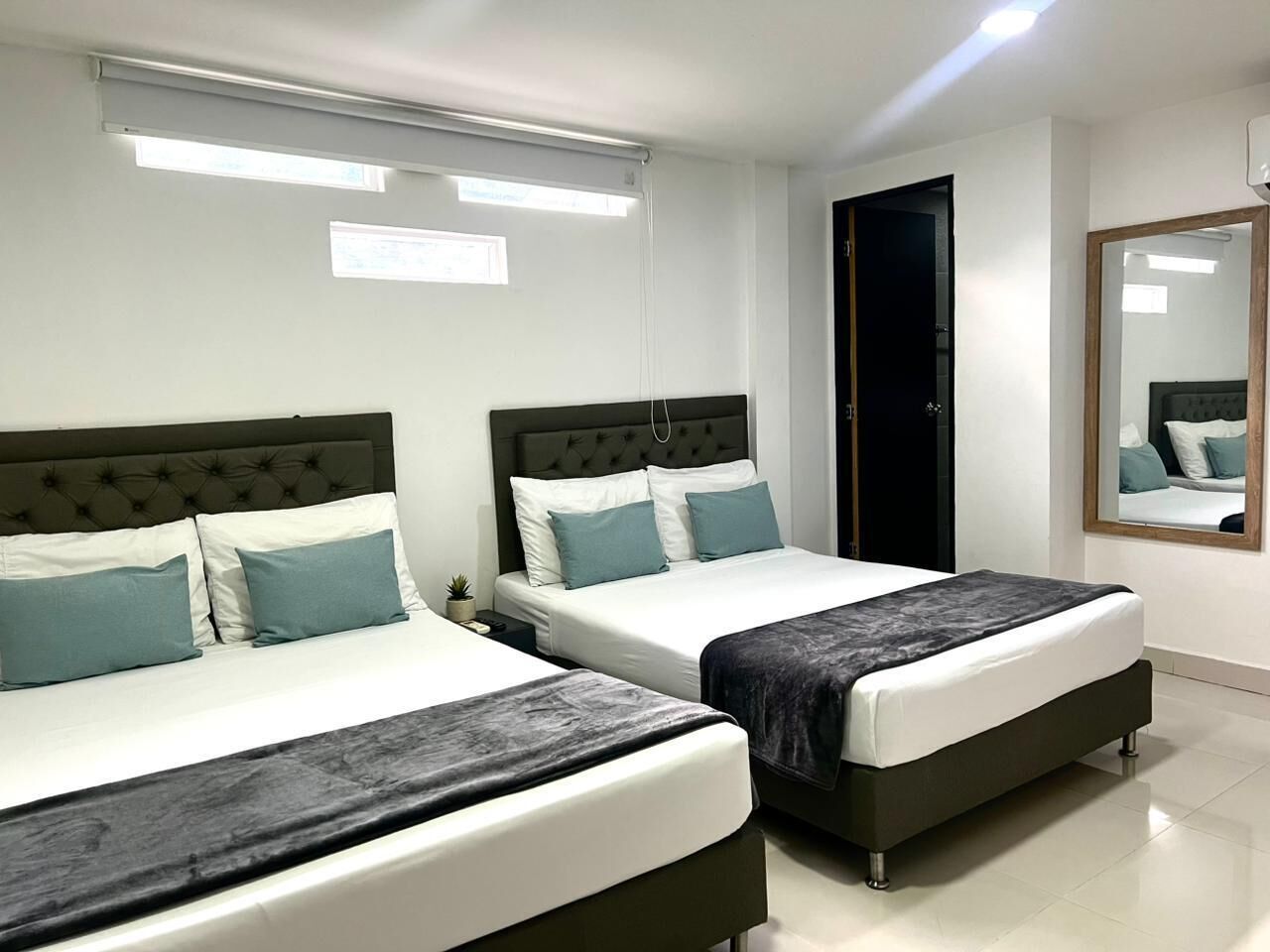 Ein Hotelzimmer mit zwei Betten, einem großen Spiegel und einer Tür.
