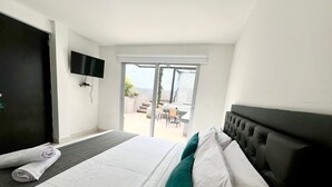 A hotel room with a bed, a TV, and a sliding glass door leading to an outdoor area. - Hotel 79 parque del poblado (Medellín)