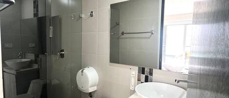 Un baño moderno con inodoro, lavabo y cabina de ducha de vidrio.