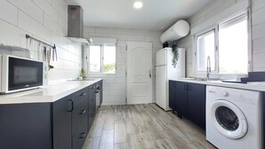 A modern kitchen with a microwave, oven, sink, and washing machine. - Stunning home in Turís (Turís)