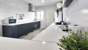 A modern kitchen with white tiles, a microwave, a toaster, and a sink. - Stunning home in Turís (Turís)