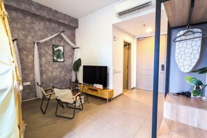 Una sala moderna con un televisor de pantalla plana, una mesa de centro de madera y una zona de estar con una silla.