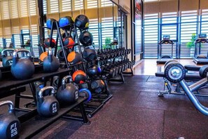 Une salle de sport équipée de kettlebells, d’haltères et d’autres appareils d’entraînement.