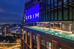 A hotel with a large illuminated sign reading 'EXSIM' and a rooftop pool area. - Forte Seasons Mossaz Premium Suites Petaling Jaya by BYON (Petaling Jaya)