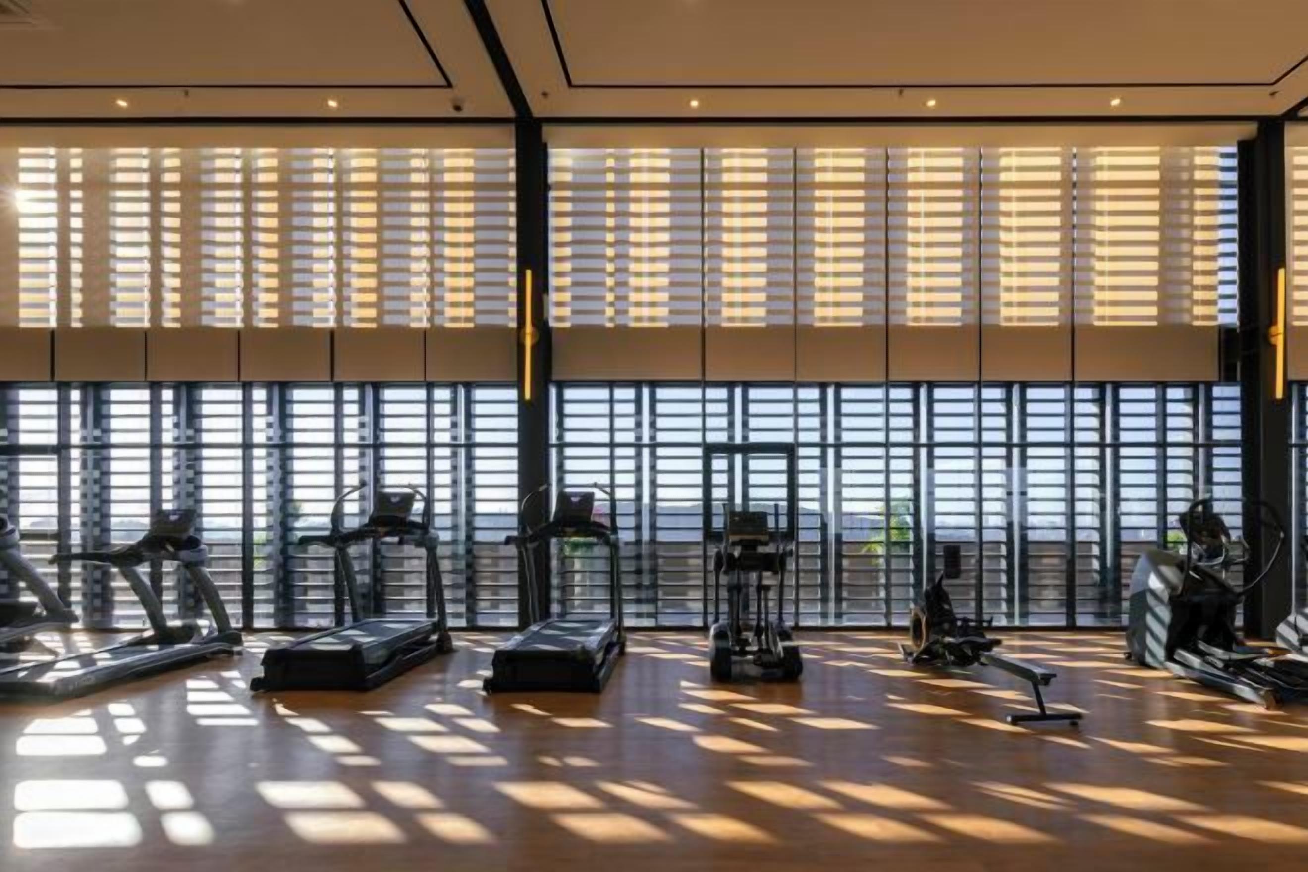 Une salle de sport équipée de matériel d’exercice et dotée de grandes fenêtres.