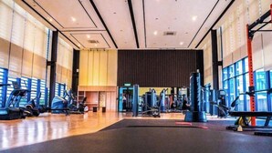 Un gimnasio con equipamiento de ejercicio, ventanas amplias y un techo alto.