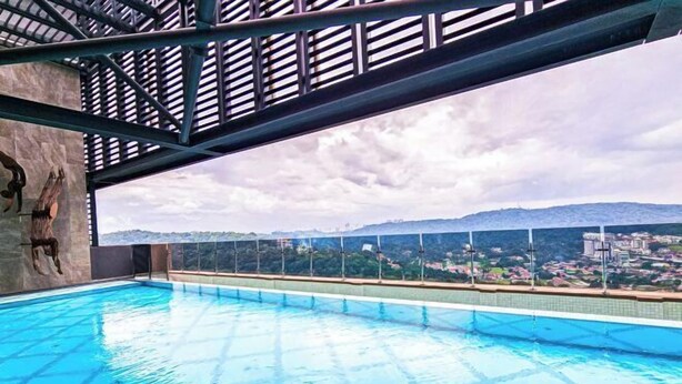 Una piscina con vistas a un paisaje urbano y montañas al fondo.