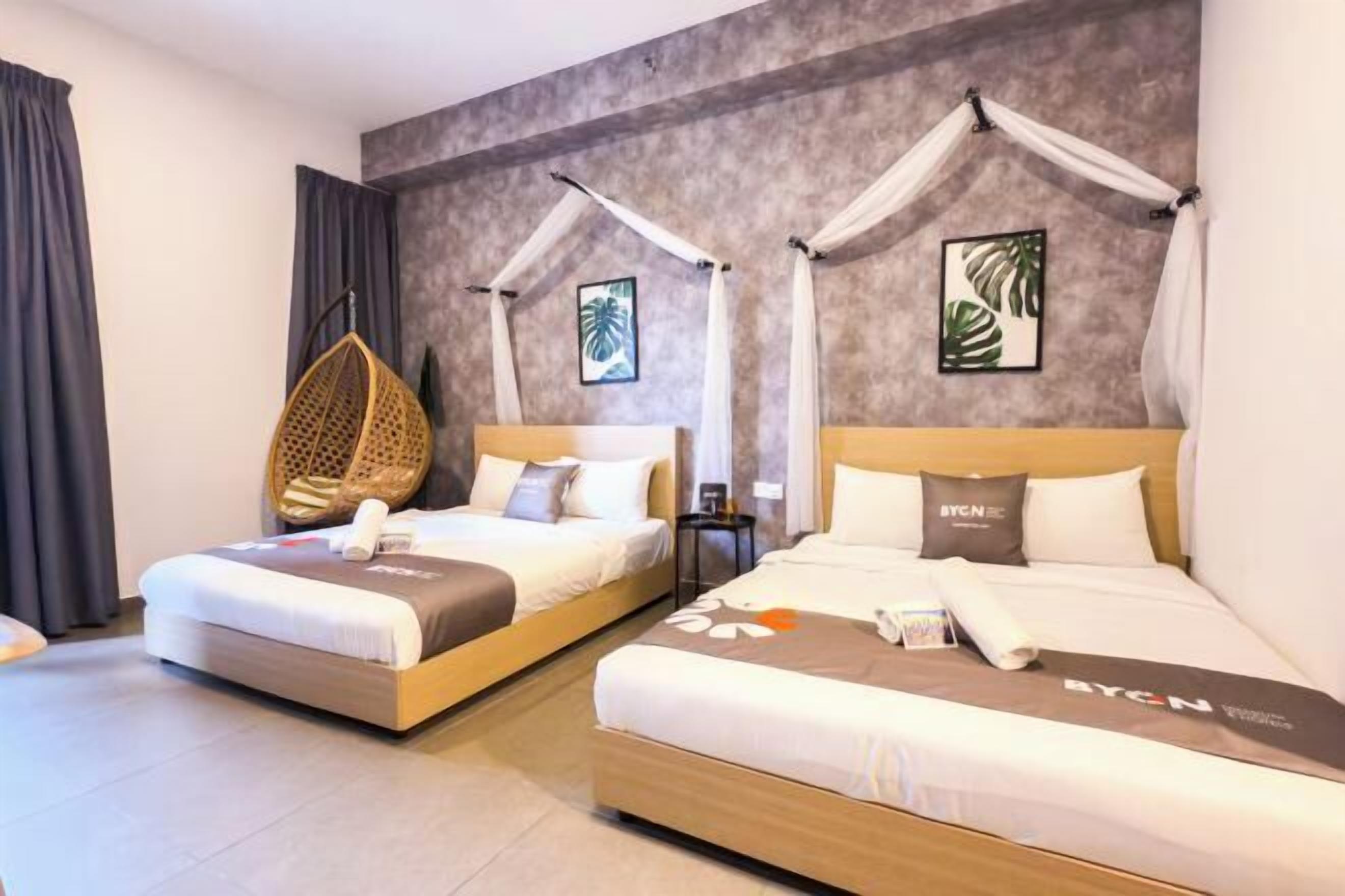 Een hotelkamer met twee bedden, elk met hemelbed, een hangstoel en kunst aan de muren.