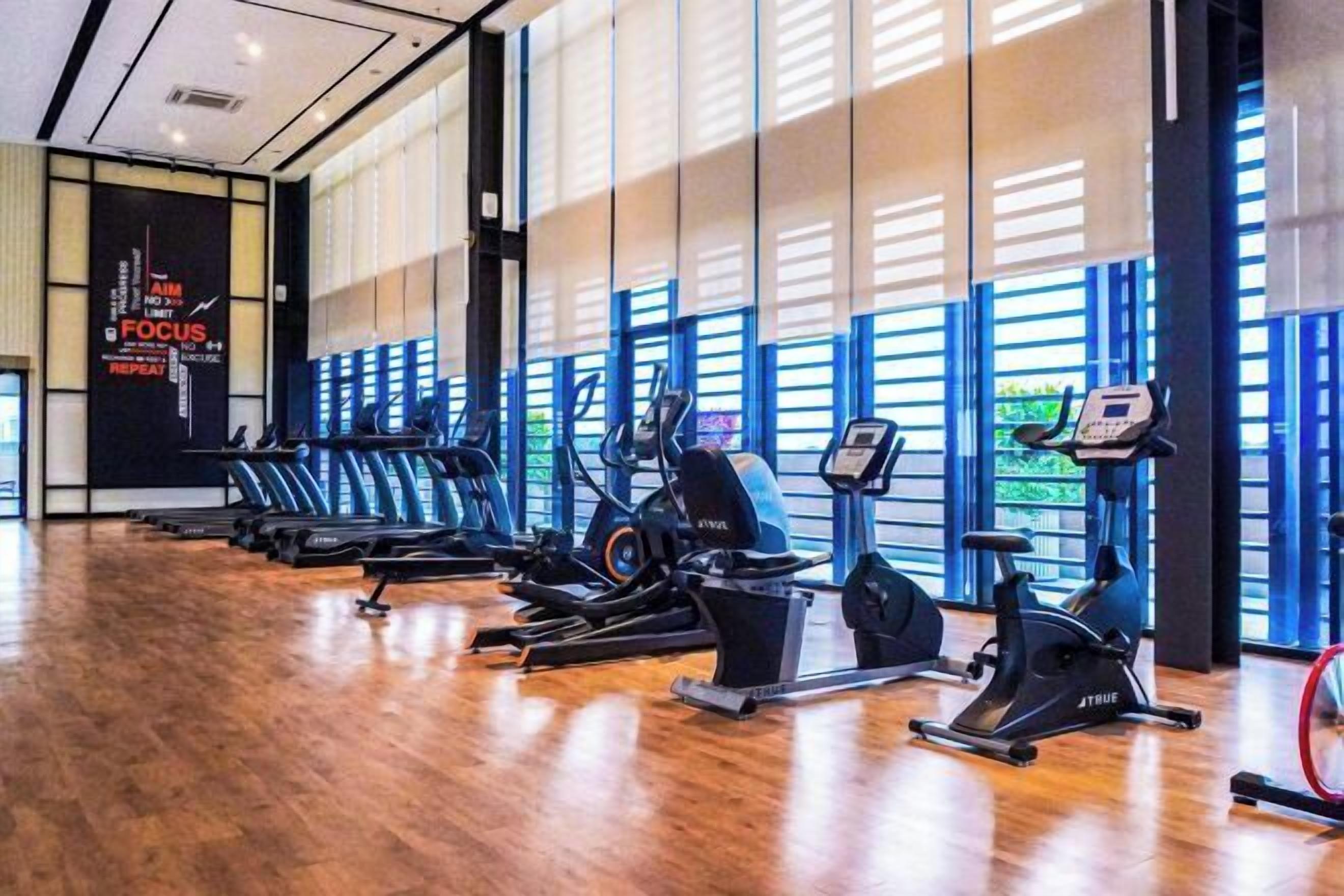 A gym with exercise equipment, large windows, and a motivational quote on the wall.