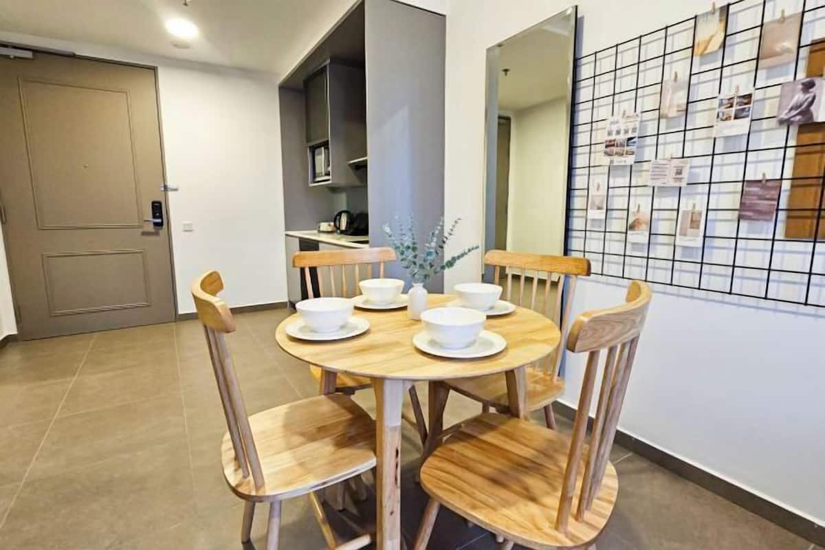 A dining area with a round wooden table, four chairs, and a vase of flowers.