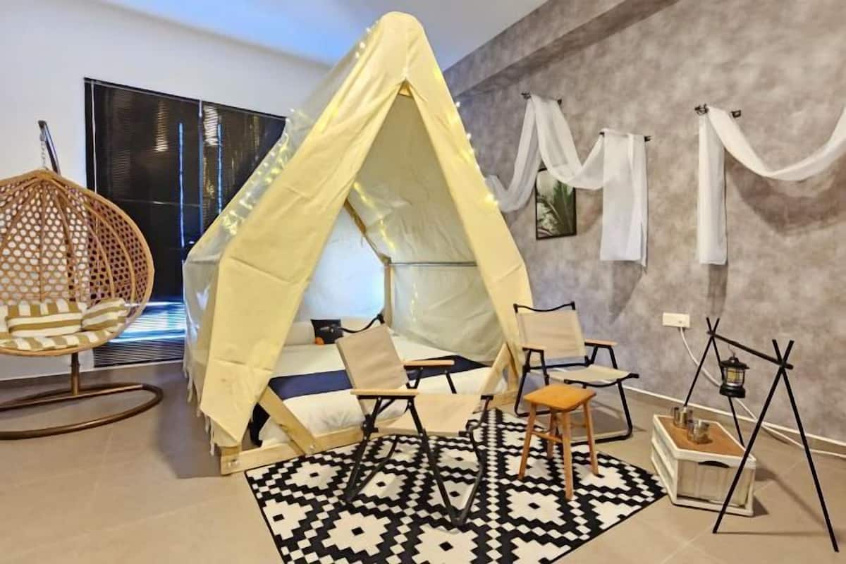 A cozy room with a canopy bed, a hanging chair, and a small table with a lantern.