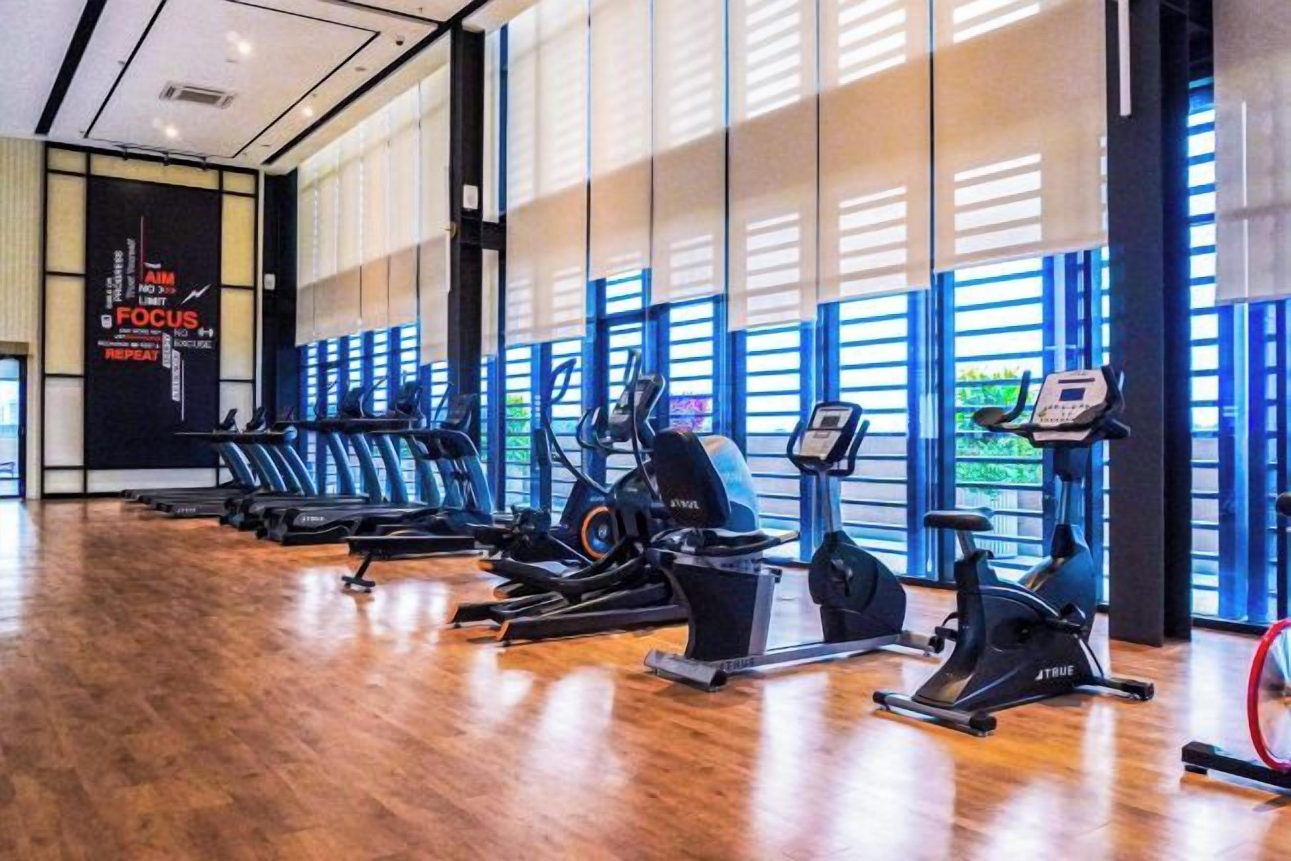 A gym with exercise equipment and large windows.