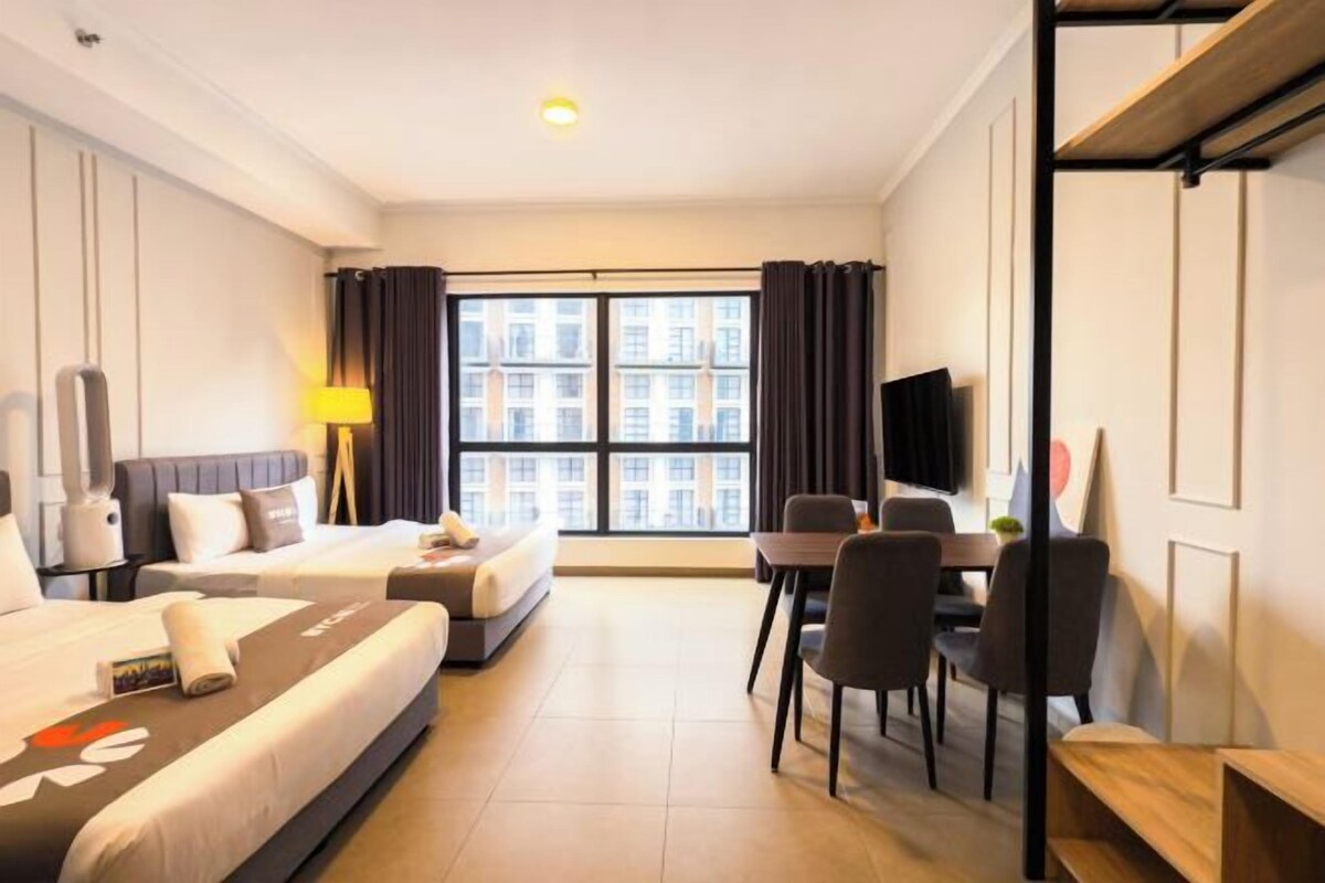 A hotel room with two beds, a desk, and a TV.