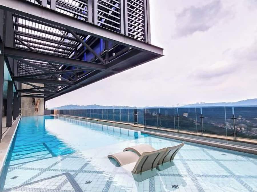 Una piscina infinita en la azotea con vistas despejadas del horizonte urbano y una cadena montañosa distante.