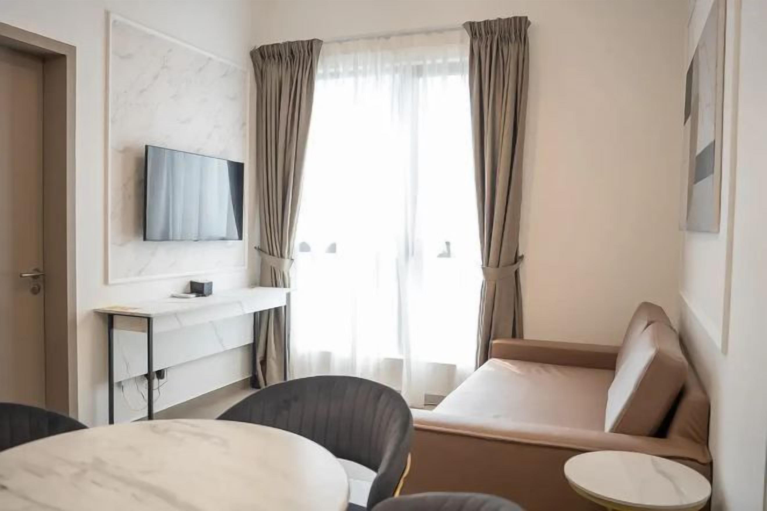 A hotel room with a bed, a TV mounted on the wall, a small table, and a chair.
