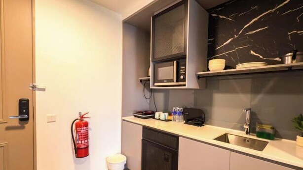 A compact kitchen with a microwave, sink, and a fire extinguisher. - Forte Seasons Mossaz Premium Suites Petaling Jaya by BYON (Petaling Jaya)
