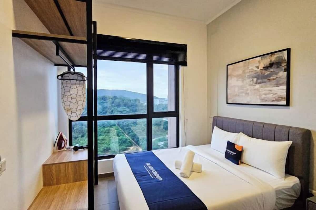 A modern hotel room with a large window offering a scenic view, a neatly made bed with a branded blanket, and a wall-mounted artwork.