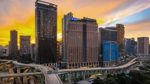 Un paisaje urbano con rascacielos, una autopista y un atardecer.